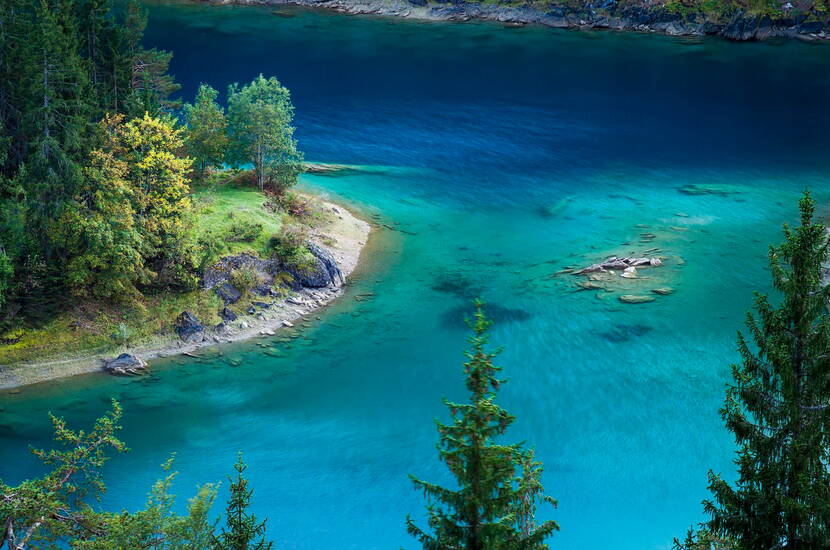 Zoom: Escursione per famiglie lago di Cauma–- Il lago di Cauma è circondato da foreste su tre lati; al centro del lago si trova un'isola boscosa. L'acqua è di un sorprendente verde turchese e piacevolmente fresca.