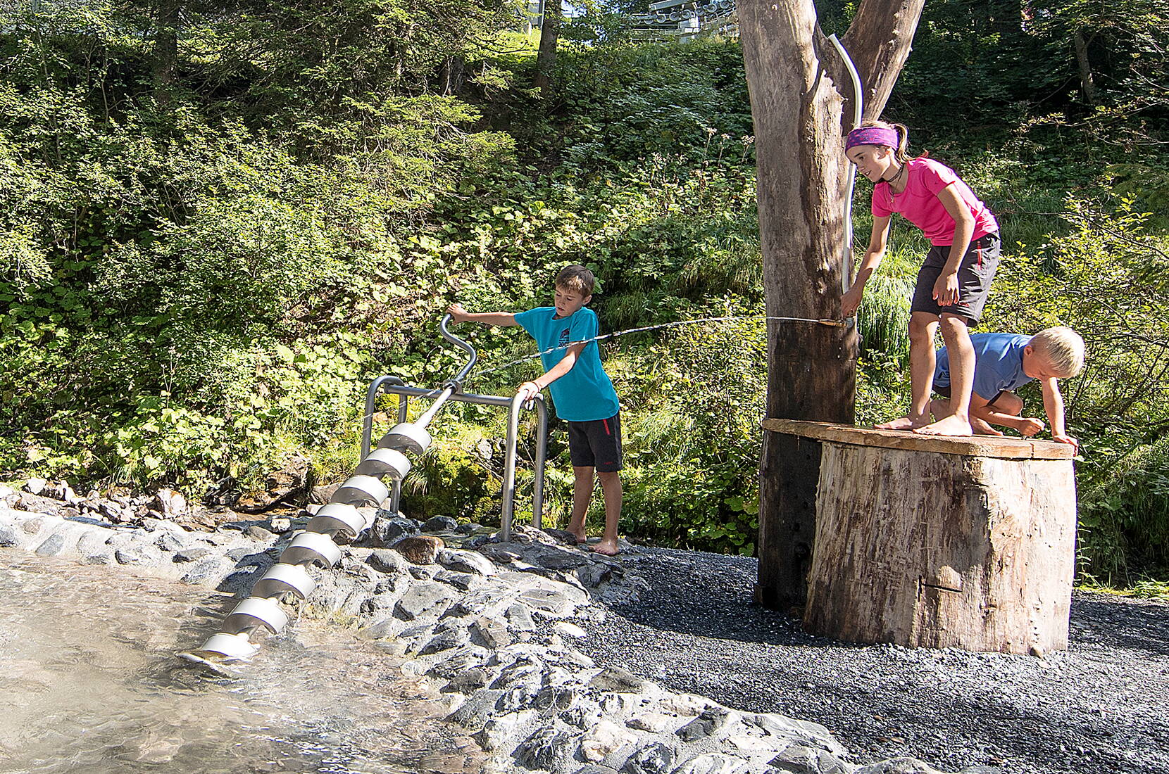 Escursione per famiglie alla foresta acquatica. Il parco giochi acquatico si trova in un'idilliaca radura forestale con un ruscello e una cascata sul guado del Pizol.