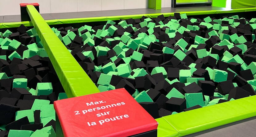 Becken gefüllt mit Schaumstoffblöcken mit einem zentralen Balken für unterhaltsame und sichere Balancier-Spiele.