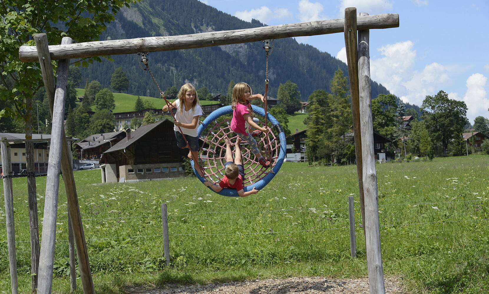 Excursion familiale aire de jeux AlpKultur Lenkerseeli. Pont suspendu, table d'eau, toboggans, sentier sensoriel, labyrinthe de haies, mikado d'escalade, bascule pour fauteuil roulant, mobile de jeu, maquette de tyrolienne, carillon, tubes rampants et balançoires permettent de passer des heures variées en plein air.