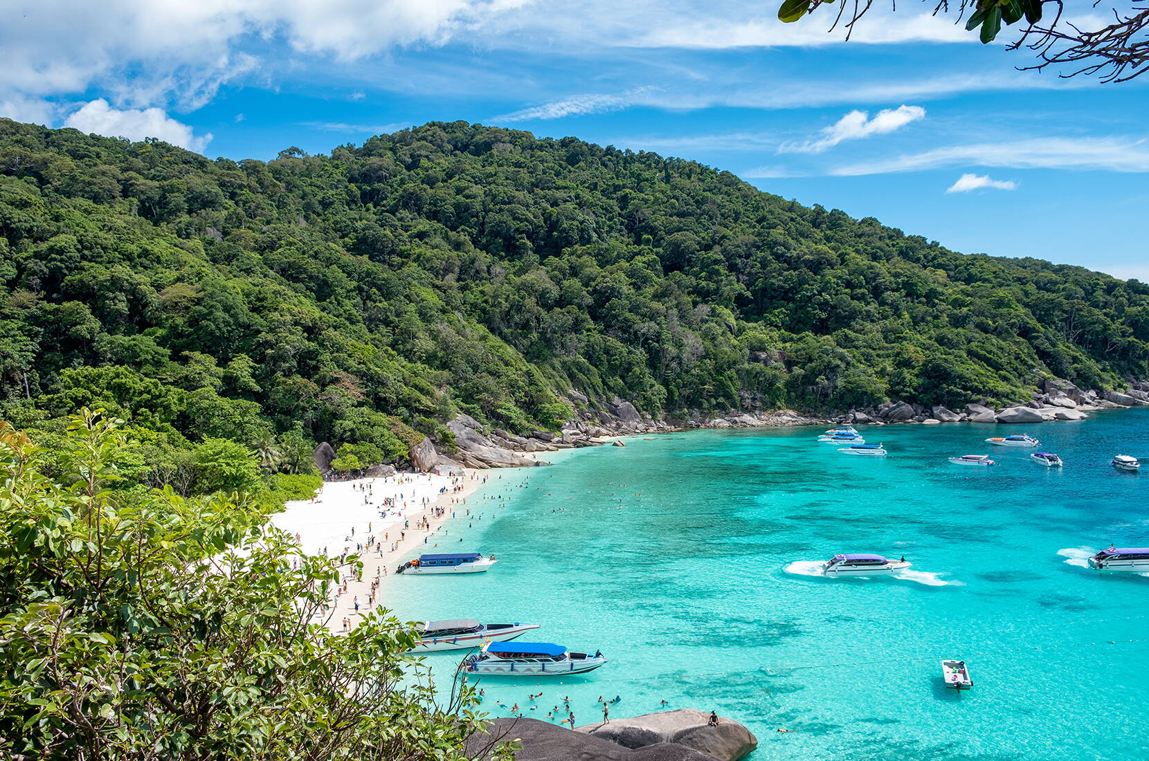 Helle Buchtlandschaft mit Felsen, blauem Wasser und schnellen Booten.