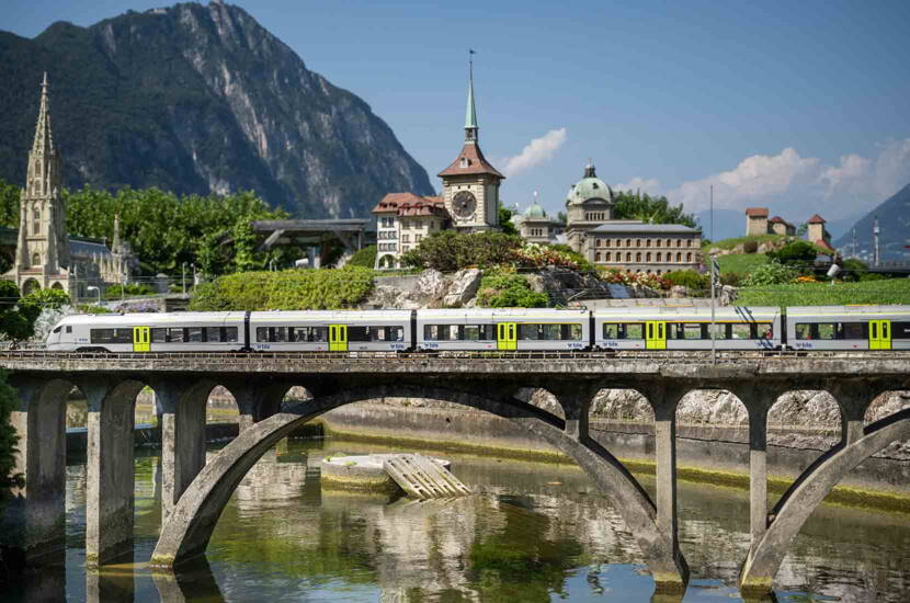 Zoom: Ein moderner Regionalzug fährt durch die Swissminiatur. Im Hintergrund sind das Berner Münster, der Zeitglockenturm und das Bundeshaus im Miniaturformat zu sehen.