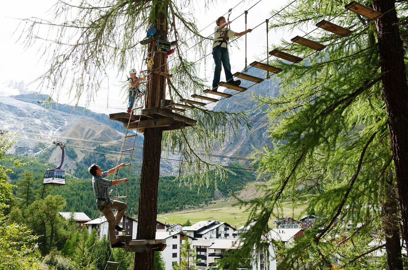 Zoom: Im Kletterpark hangelt man sich von Baum zu Baum und überwindet verschiedene Hindernisse in den Baumwipfeln.