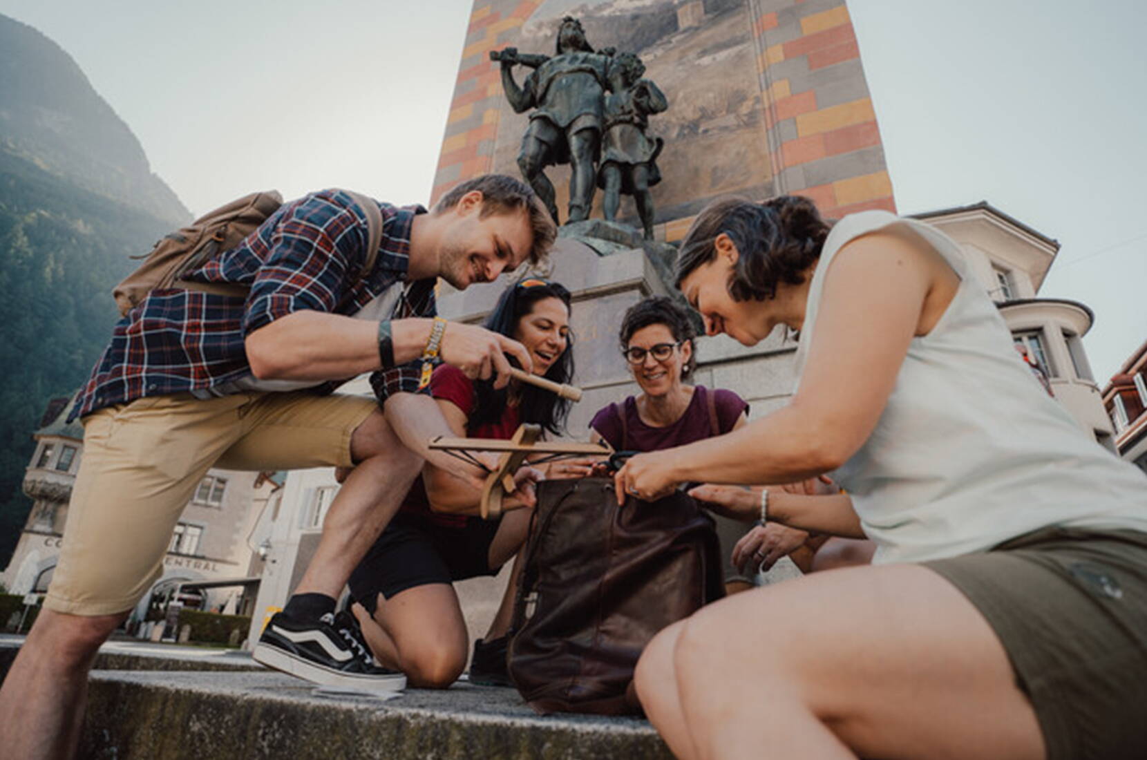 Groupe assis au pied du célèbre monument de Tell à Altdorf fouille avec concentration le sac à dos de commissaire avec cartes de jeu et documents d'enquête