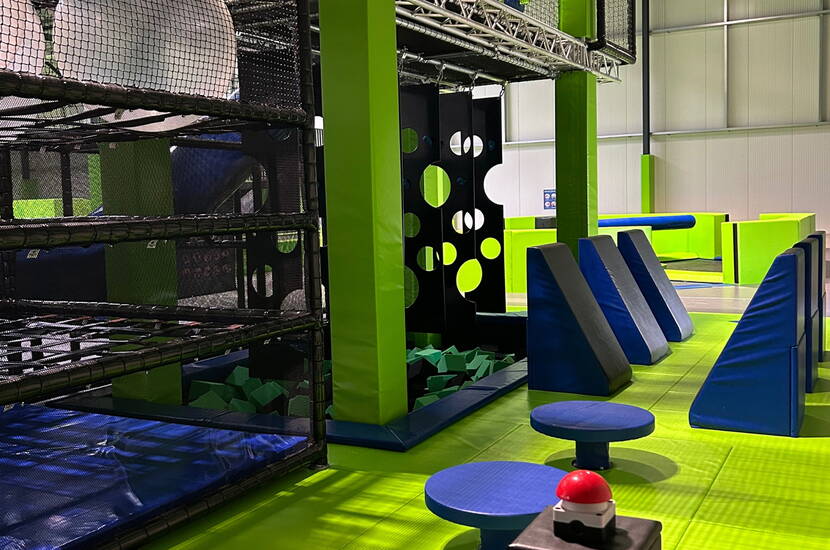 Zoom: Zone de jeu dynamique avec structures d’escalade, blocs rembourrés et plateformes colorées pour des défis amusants et sécurisés.