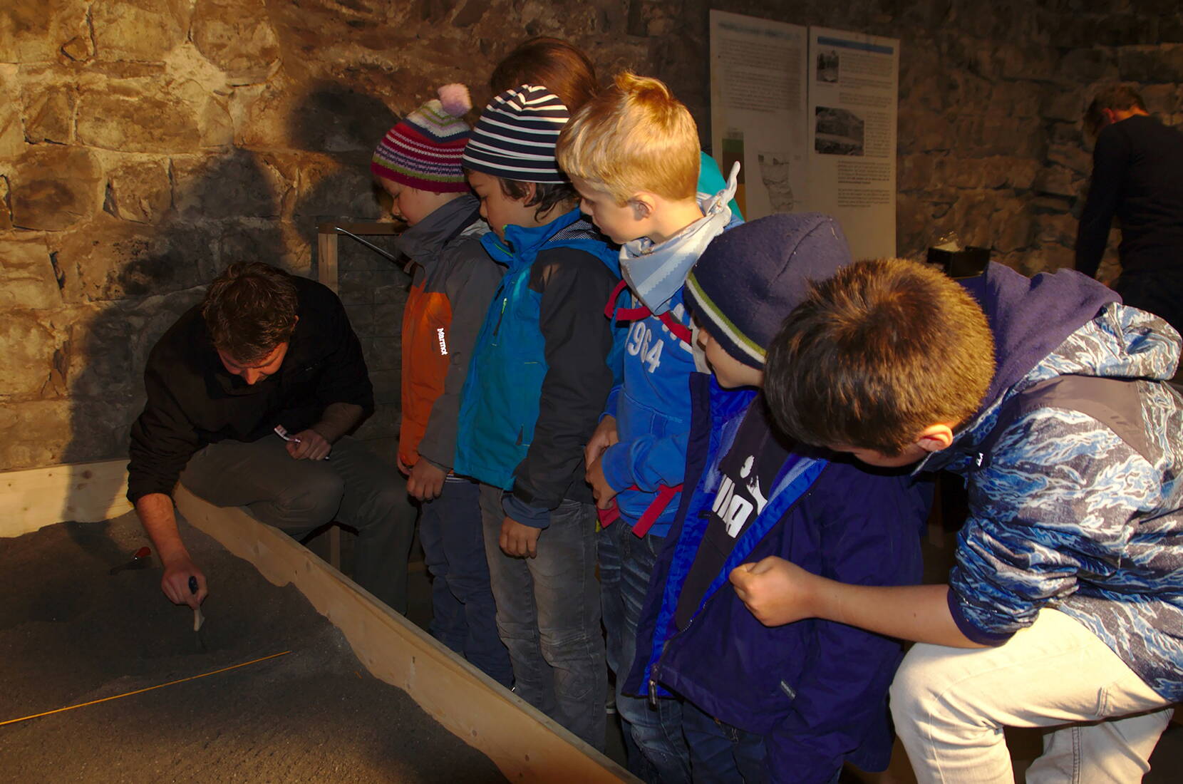 Familienausflug Schloss Werdenberg. Kleine ArchäologInnen heben unter der Leitung einer Fachperson entdeckte Fundstücke korrekt aus der Erde, ordnen sie und besprechen deren Bedeutung.