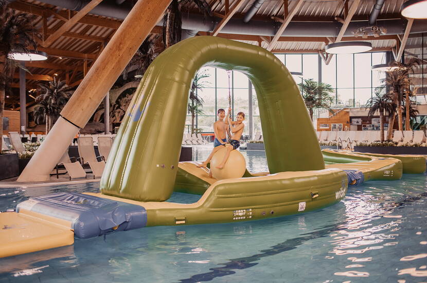 Zoom: Kinder balancieren auf einer grossen aufblasbaren Insel im Innenbecken.
