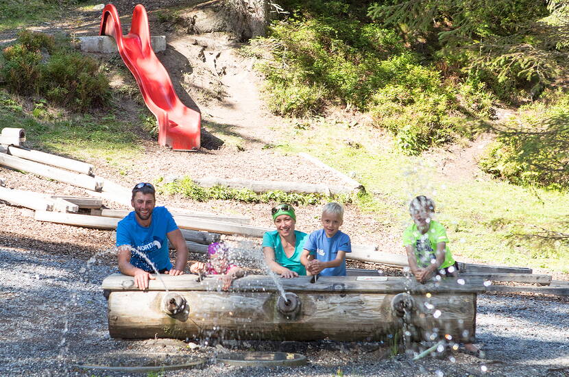 Zoom: Excursion familiale dans la forêt d'eau. L'aire de jeux aquatiques se trouve dans une clairière idyllique avec un ruisseau et une cascade sur le gué du Pizol.