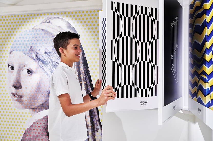 Person dreht ein Musterpanel in einer interaktiven Ausstellung mit optischen Täuschungen.