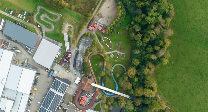 Die Drohnenaufnahme zeigt den weitläufigen Erlebnispark mit Rodelbahn, Spielbereichen und grüner Umgebung in der Zentralschweiz.