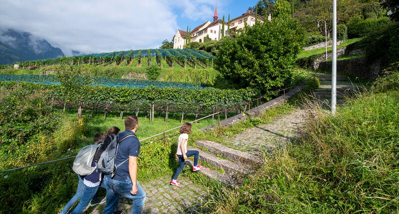 Famiglia durante caccia al tesoro Dov'è Walterli attraverso vigneti di Altdorf Uri con panorama montano