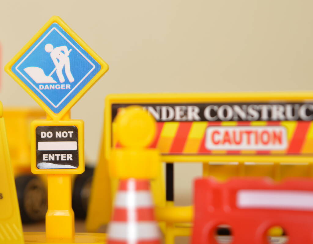 Spielzeug-Baustellenschilder in Gelb mit Symbolen für Danger, Do not enter, Under Construction und Caution als Hinweis auf den Aufbau des neuen Flipped Funpark Aussenbereichs BALAMBA