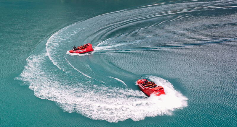 Zwei Jetboats drehen weite Kreise und erzeugen Wasserwirbel auf dem Brienzersee – idealer Blick auf Action‑Manöver und türkises Wasser.