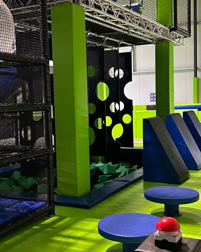 Zona gioco dinamica con strutture da arrampicata, blocchi imbottiti e piattaforme colorate per sfide divertenti e sicure.