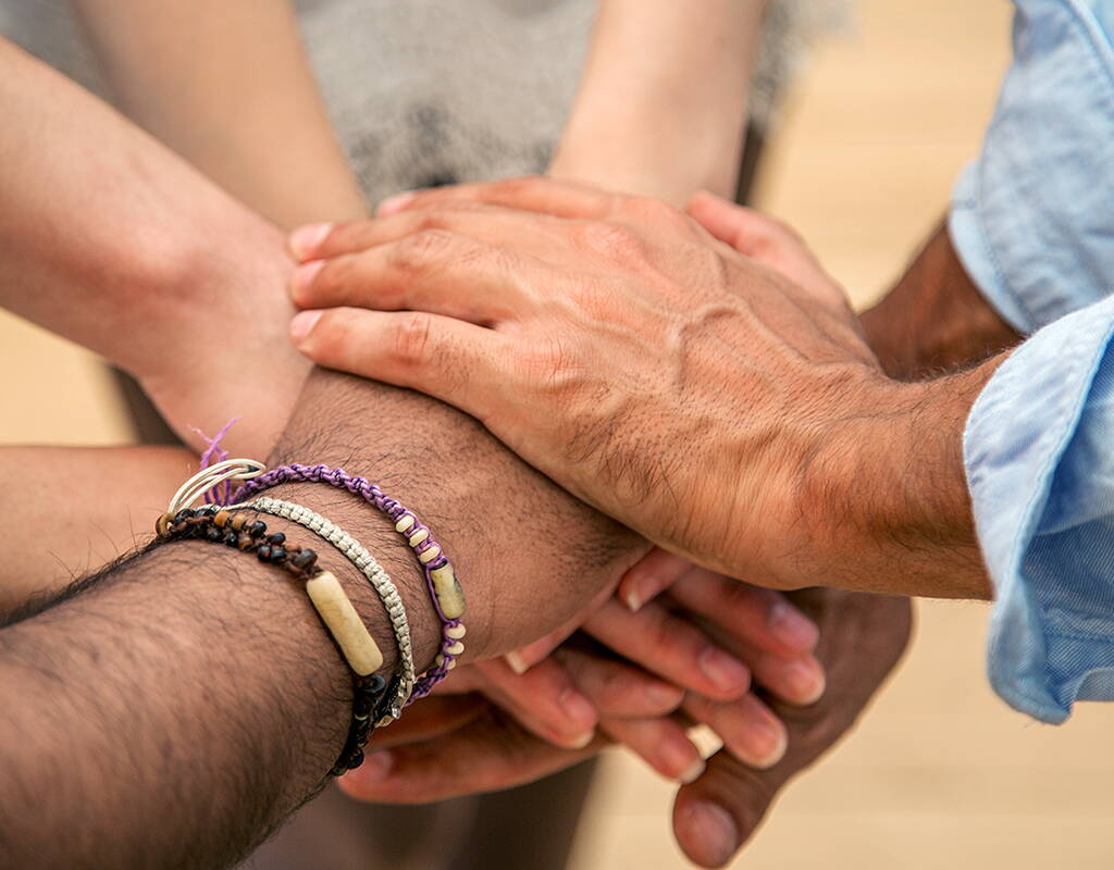 Plusieurs mains posées les unes sur les autres symbolisent la solidarité, la confiance et une collaboration partenariale.