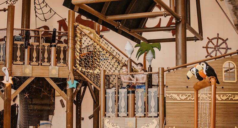 Vista dettagliata della nave dei pirati con ponti in legno, reti e figure colorate.