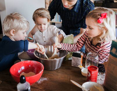 Backen mit den Kindern Vater mit drei Kindern bereiten einen Teig vor.
