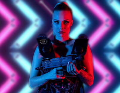 Una persona con l’attrezzatura da laser game si trova davanti a una scenografia luminosa e si prepara a giocare.