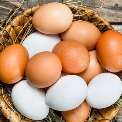 Un cestino intrecciato pieno di uova bianche e brune, ideali per una colorazione e decorazione naturale.