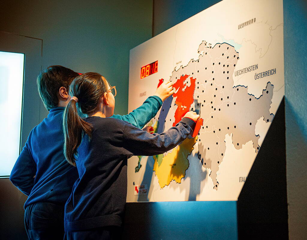 Spielerische Aktivität mit einer Schweiz‑Karte zur Veranschaulichung der historischen Landesverteidigungsstrategie.