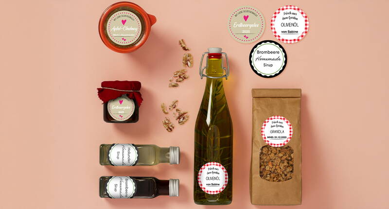 Verschiedene Gläser, Flaschen und Beutel mit individuell gestalteten, runden Stickerella‑Etiketten – perfekt für Konfitüre, Öl, Sirup und Granola. Die Etiketten zeigen, wie stilvoll Swiss‑Made‑Sticker Selbstgemachtes veredeln.