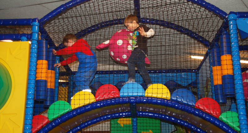 Bambini che giocano e si arrampicano sulle strutture colorate del parco giochi indoor del Parco animali e avventura Seeteufel.