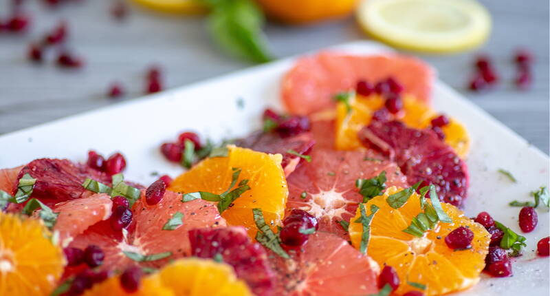 Perfekt für den Sommer. Ein erfrischender Zitrusfruchtsalat mit Granatapfel und Basilikum. 