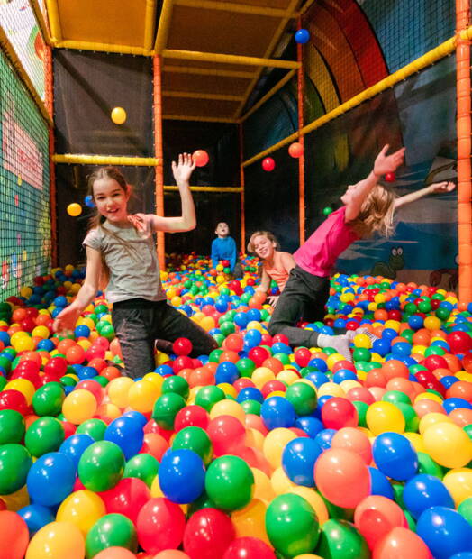 Bambini giocano in una colorata vasca delle palline in un parco giochi indoor – un’attività popolare ed economica per le famiglie in Svizzera, spesso disponibile con buoni o sconti.