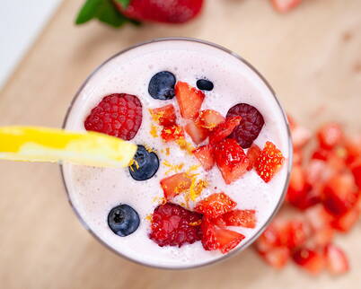 Eine Handvoll gemischte Beeren, eine Messerspitze Zitronenabrieb, eine halbe Tasse Mandelmilch, eine Portion Eiweisspulver und einige Eiswürfel in einen Mixer geben und gut durchmixen. Optional können einige Blätter Spinat oder Grünkohl für zusätzliche Vitamine und Mineralstoffe hinzugefügt werden.