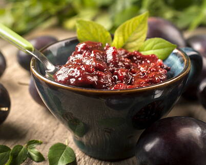 Eine Schale mit selbstgekochtem Pflaumenchutney, umgeben von frischen Pflaumen – perfekt als Brotaufstrich oder zum Weiterverarbeiten.