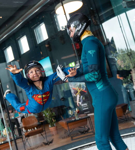 Un bambino prova l’indoor skydiving in una galleria del vento con istruzione – un’attività speciale per famiglie in Svizzera, resa accessibile grazie a buoni o sconti.