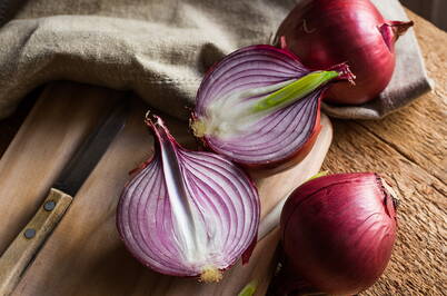 Cipolle rosse tagliate su un tagliere, un ingrediente classico per uno sciroppo naturale contro la tosse.
