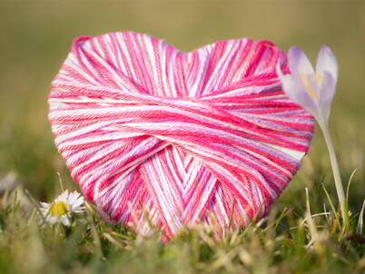 Herzförmiges Bastelmotiv aus rosa Garn als symbolische Muttertags‑Bastelidee für ein persönliches Geschenk.