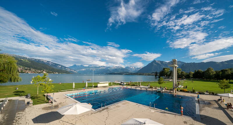 Destinazioni delle escursioni Berna – Gita in famiglia lido di Thun. Lo «Strämu» di Thun si estende su 50.000 m² e offre una vista mozzafiato sulle Alpi e sul Lago di Thun! Sul retro del prato si trova la zona per bambini e famiglie con una piscina per non nuotatori e aree ombreggiate per prendere il sole sotto gli alberi.