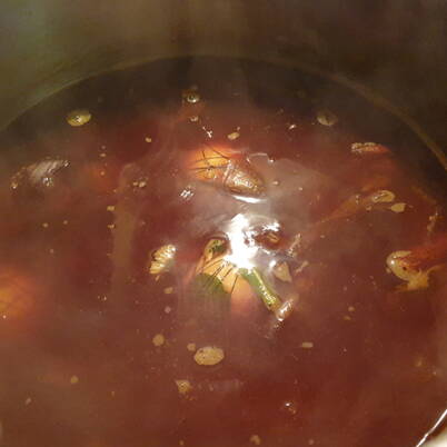 Ein dampfender Topf mit dunklem Zwiebelschalen‑Sud, in dem sich Pflanzenteile und Farbstoffe vermischen.