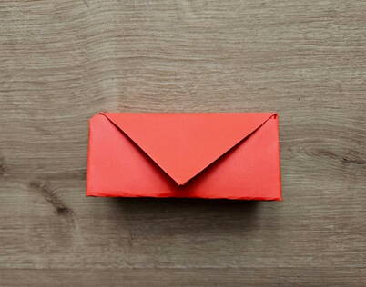 Fertiges DIY Papierportemonnaie – Origami Geldbeutel mit Verschlussklappe Das vollständig gefaltete Papierportemonnaie zeigt eine saubere, dreieckige Verschlussklappe, die das Innere sicher schützt. Die kompakte Origami‑Form eignet sich perfekt als kleines DIY‑Portemonnaie für Gutscheine, Geldscheine oder Nachrichten. Dieser letzte Schritt vollendet das einfache, aber stilvolle Papierprojekt.