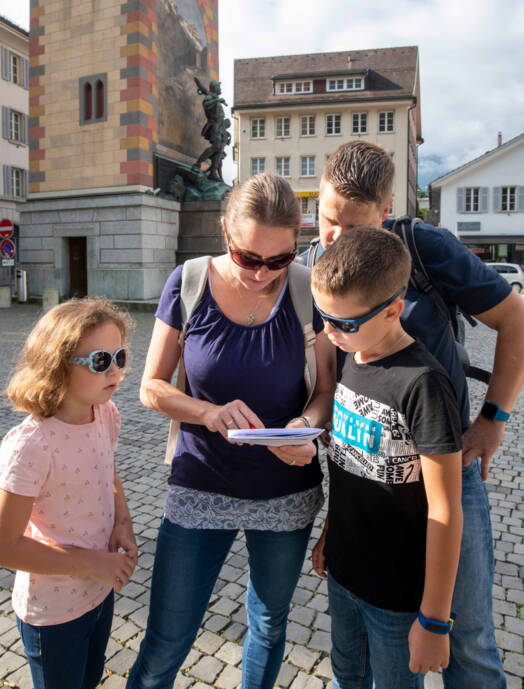 Una famiglia segue indizi durante una caccia al tesoro in un centro storico svizzero – un’attività entusiasmante e spesso gratuita, ideale per gite economiche con bambini.