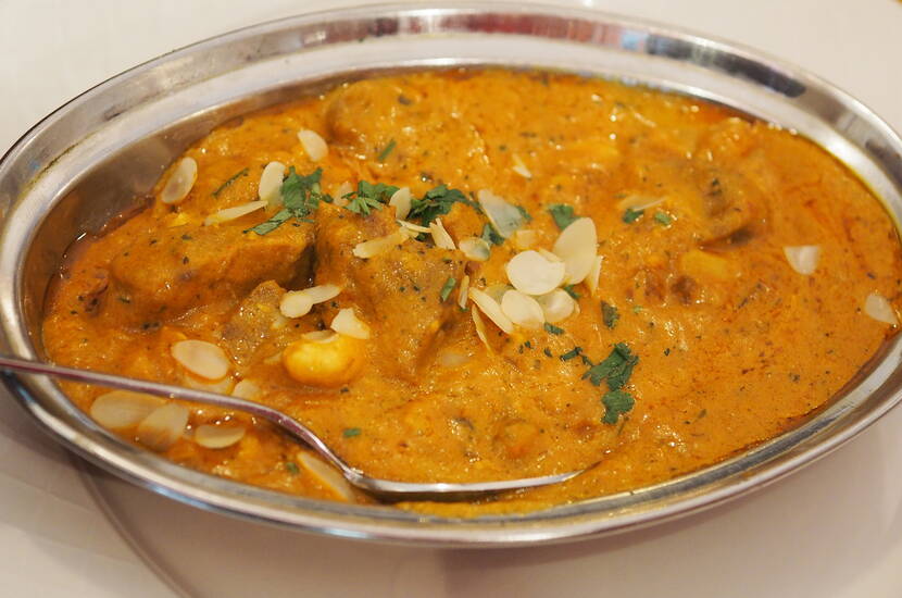 Das bemehlte Lammfleisch in Öl andünsten, aus der Pfanne heben und beiseite stellen. Zwiebel- und Knoblauchwürfel in Öl andünsten, Currymischung beifügen und kurz mit dünsten (Achtung: wenn sie verbrennt, wird sie bitter). F