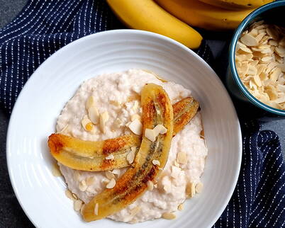 Porridge mit karamellisierter Banane Ein Schüssel Porridge, liebevoll dekoriert mit karamellisierten Bananenscheiben und Mandelblättchen – süss, warm und besonders aromatisch.