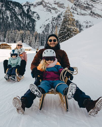 Plusieurs personnes descendent une pente enneigée en luge et savourent une journée hivernale.
