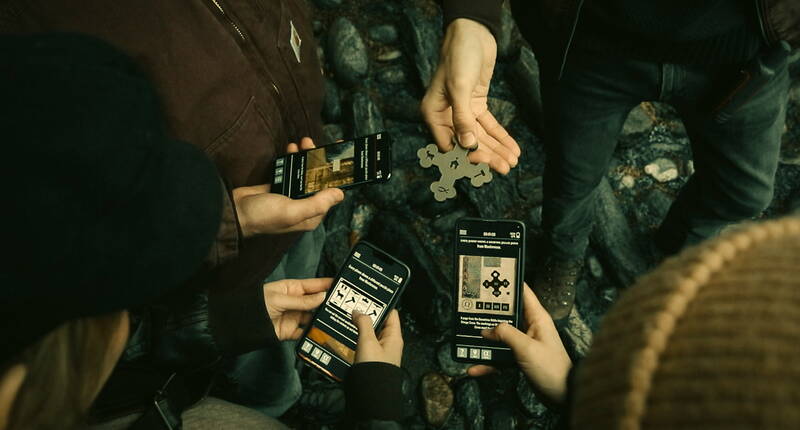 Spieler lösen gemeinsam Rätsel beim Sato Code Outdoor Escape Game. Die App führt durch spannende Herausforderungen, während physische Puzzle-Teile kombiniert werden müssen – perfektes Teamwork für das interaktive Stadterlebnis.