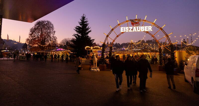 Ingresso illuminato della Magia del Ghiaccio Lucerna con arco festivo e visitatori al tramonto, pattinaggio gratuito per tutti