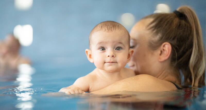 Un bébé découvre la douceur de l’eau dans les bras d’un adulte. Une activité qui favorise la confiance et le bien-être dès le plus jeune âge.