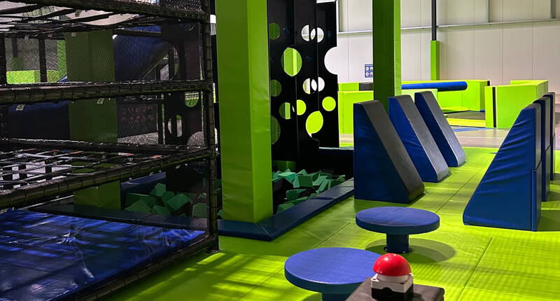 Zone de jeu dynamique avec structures d’escalade, blocs rembourrés et plateformes colorées pour des défis amusants et sécurisés.