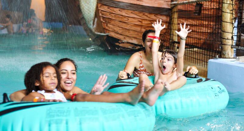 Un groupe de visiteurs glisse sur de grandes bouées à travers la zone de divertissement aquatique.