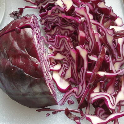 Mehrere dünn geschnittene Rotkabistreifen liegen auf einer Schneidefläche – Grundlage für den blaufärbenden Sud.
