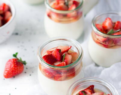 Joghurt mit frischen Erdbeeren In Gläser abgefülltes Naturjoghurt, getoppt mit geschnittenen Erdbeeren und Rosmarin