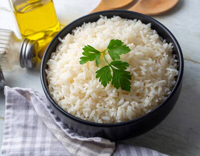 Riz blanc cuit avec persil dans un bol noir – doit être emballé encore tiède et se conserve 1-2 jours au réfrigérateur