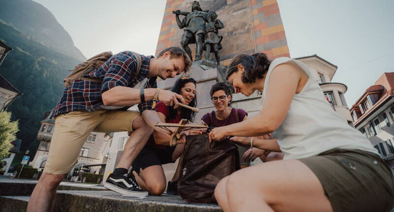Sur l'image, on voit un groupe devant le monument de Tell à Altdorf.