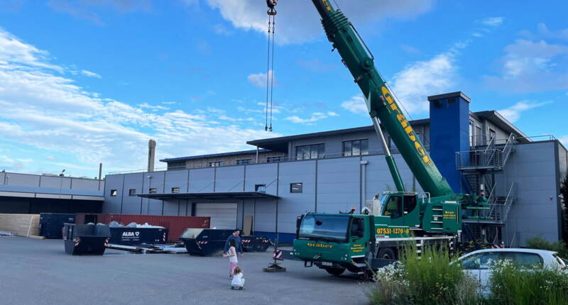 Grüner Kranwagen im Flipped Funpark in Singen beim Bau des neuen Aussenbereichs BALAMBA, mit Kindern und einer Müllmulde auf dem Gelände
